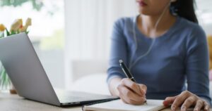 A young employee writing in a notebook to upskill.