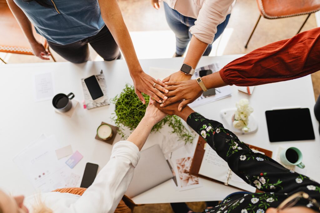 A group of employees placing their hands together showing positive team culture.
