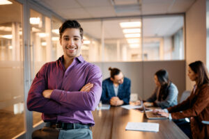 Young professional smiling confidently in a modern office while starting a full-time job.